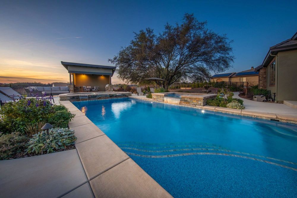Rectangular fiberglass pool with waterfall on side and attached spa and waterfall at far end
