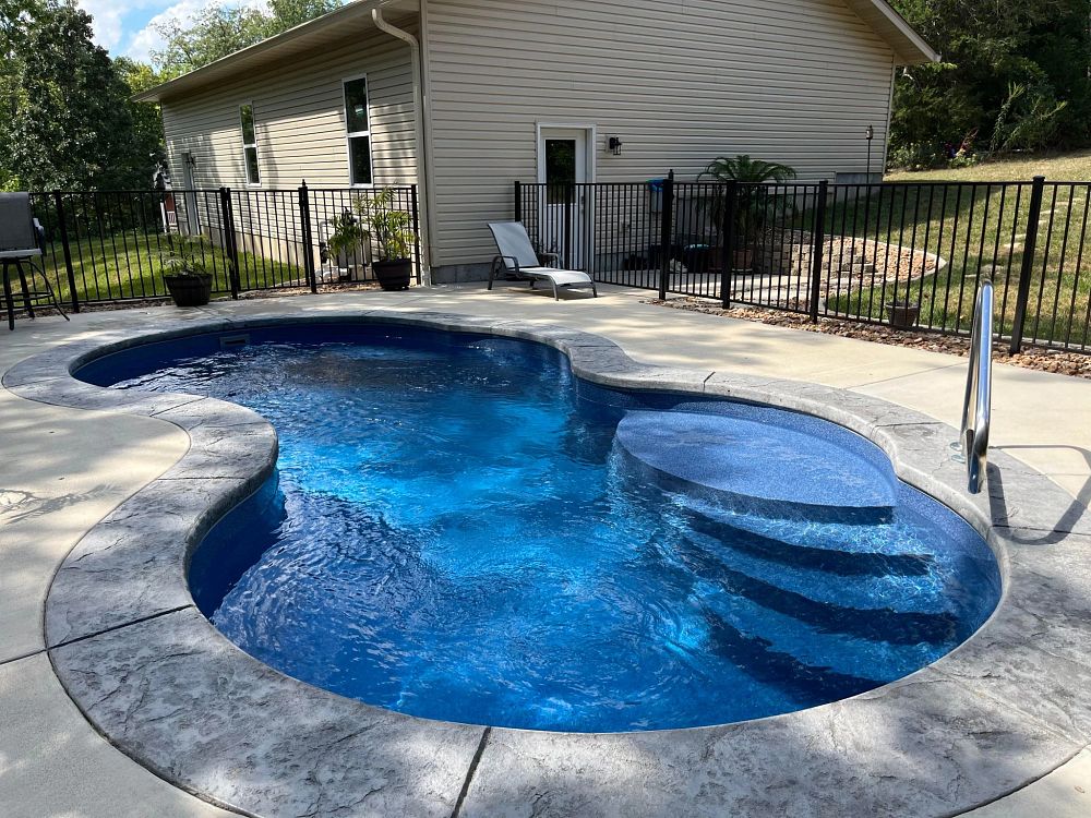 freeform fiberglass pool in compact backyard