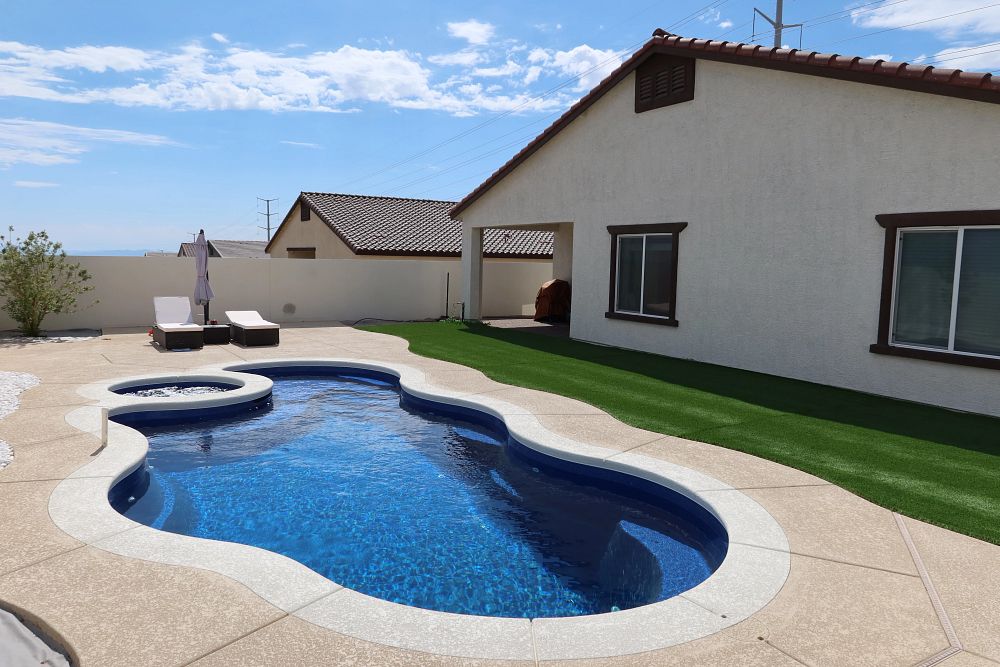 small fiberglass pool with spa in western backyard