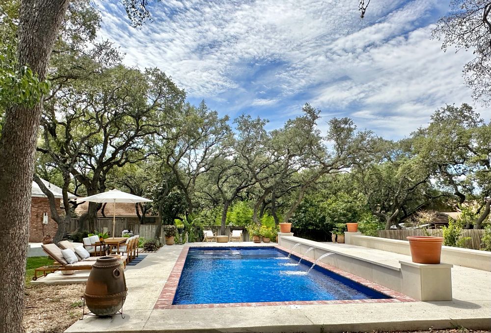 rectangular fiberglass pool with custom water features and nice landscaping