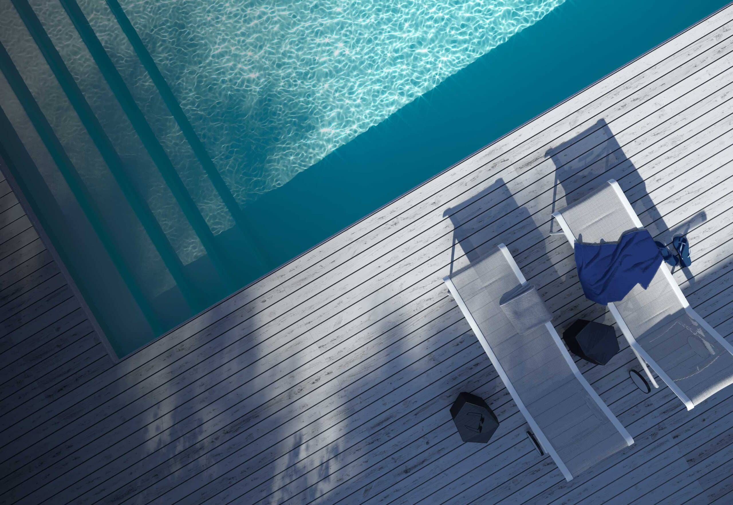 Two lounge chairs next to an inground pool in a residential backyard.