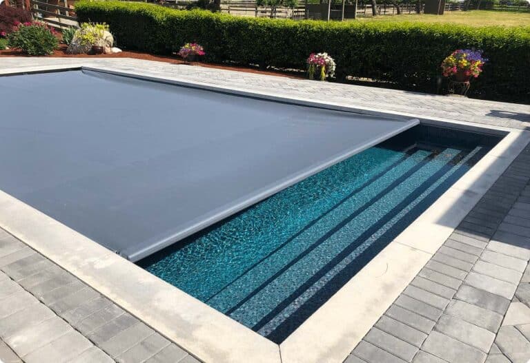 Automatic safety cover closing over an inground pool.