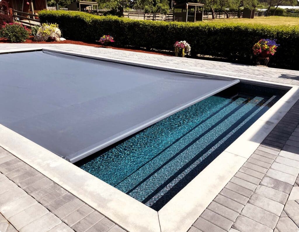 Automatic safety cover closing over an inground pool.