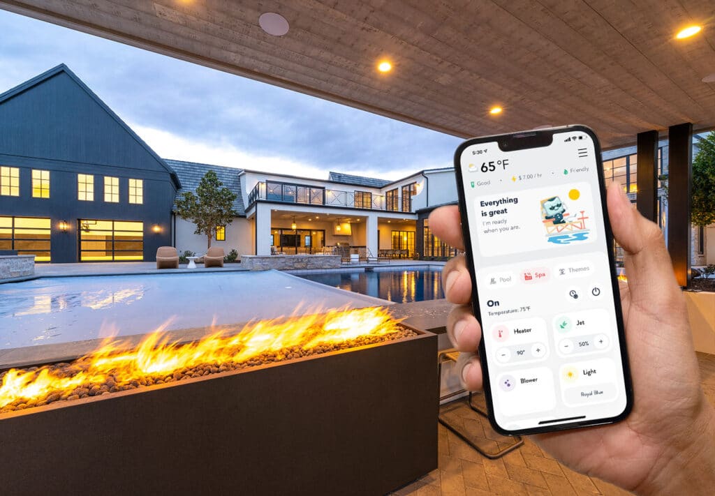 Handing holding a cell phone with The Attendant app on screen, in front of a fire feature
