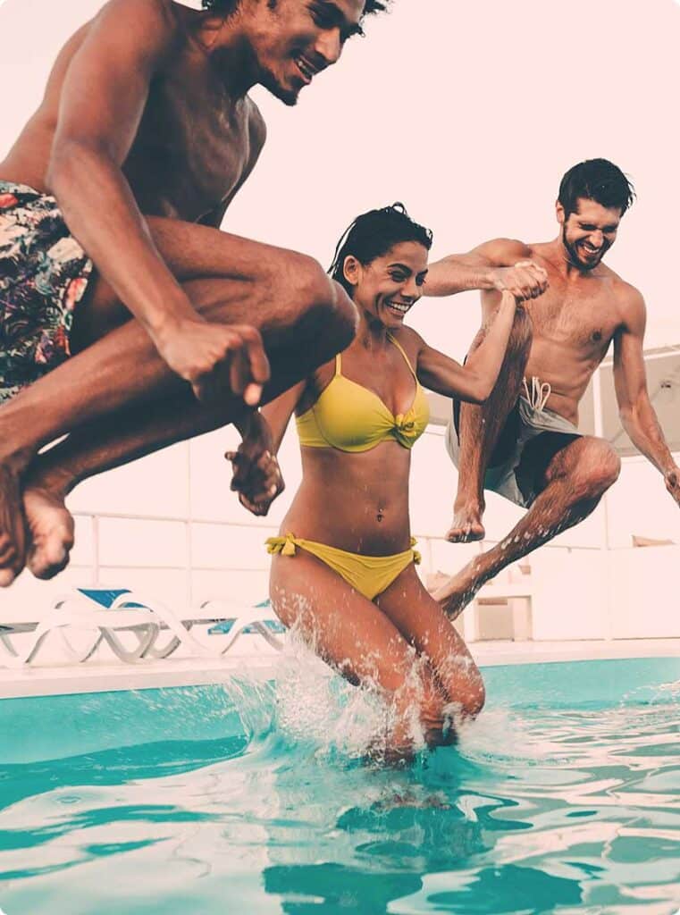 Young adults jumping into inground swimming pool