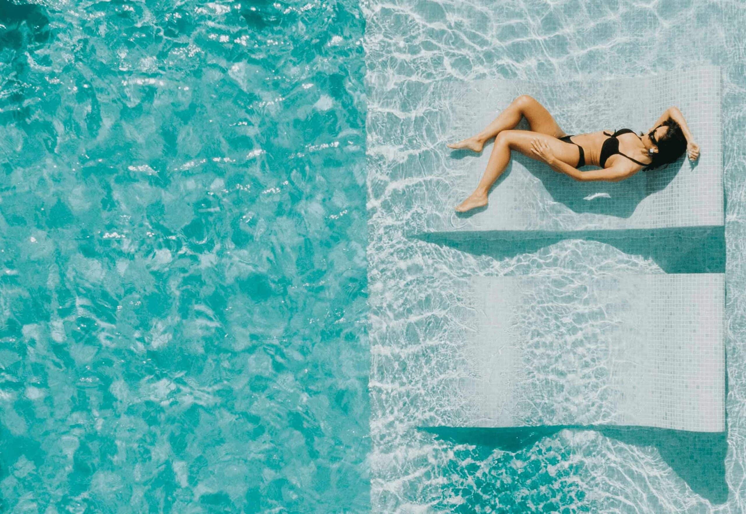 large inground pool with built in tanning ledge with woman laying down